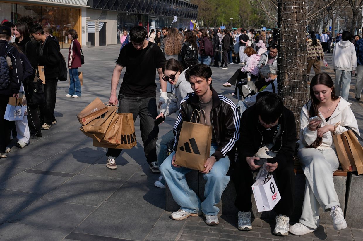 Foreign tourists with their purchases gather at a popular outdoor shopping mall in Beijing on Saturday, April 4, 2026. -- AP Photo/Andy Wong