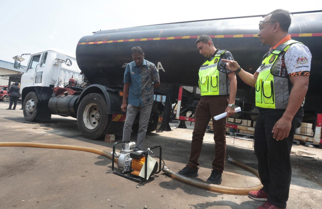 Penang Domestic Trade and Cost of Living Ministry director S. Jegan (left) and enforcement officers (in neon vests) looking at the hoses and a pump unit used to transfer diesel from one tanker to the other during the press conference held at the Penang Domestic Trade store in Butterworth, Penang. - Photos by ZHAFARAN NASIB/The Star
