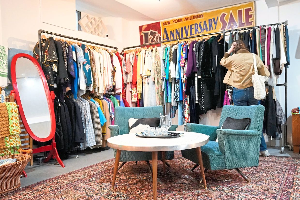 A shopper looks at a rack at Mothership, a vintage and thrift store, Thursday, March 26, 2026, in New York. (AP Photo/Alyssa Goodman)