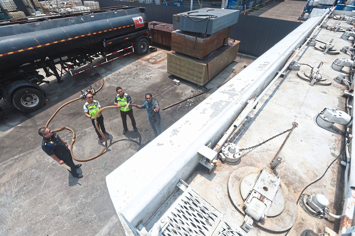 Secret plan: Jegan (extreme right) and KPDN enforcement officers demonstrating how the diesel was pumped between the tankers to be transported illegally out of Penang. — ZHAFARAN NASIB/The Star