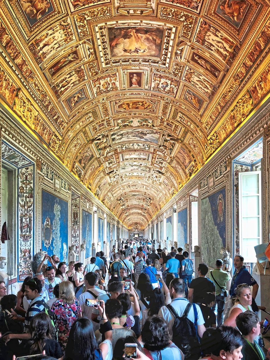 Visitors at one section of the Vatican Museums admiring the frescoes.