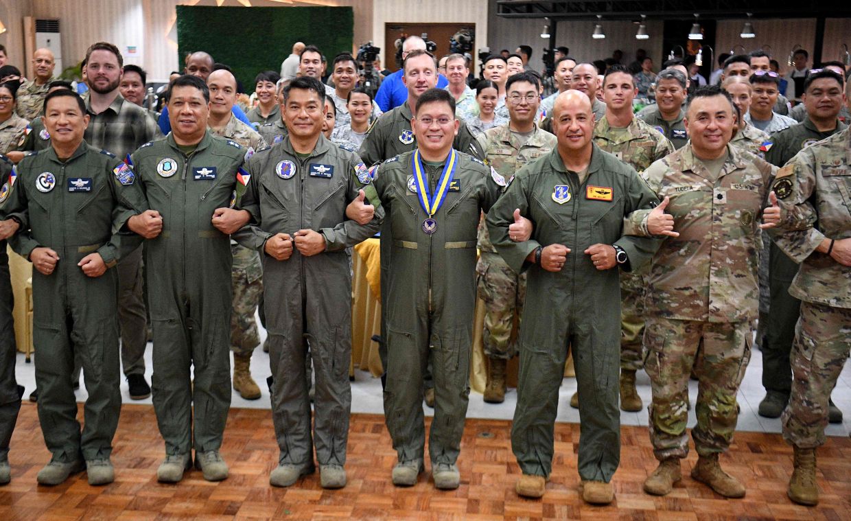 Philippine and US air force officers led by US Brigadier General Phillip Mallory (3rd R) Pacific Air Force head of delegation, and Philippine Major General Dennis Estrella (4th R), commander of Air logistics command, join hands during the opening ceremony of the COPE Thunder exercise at Clark air base in Angeles city, Pampanga province on Monday, April 6, 2026. -- Photo by Ted ALJIBE / AFP
