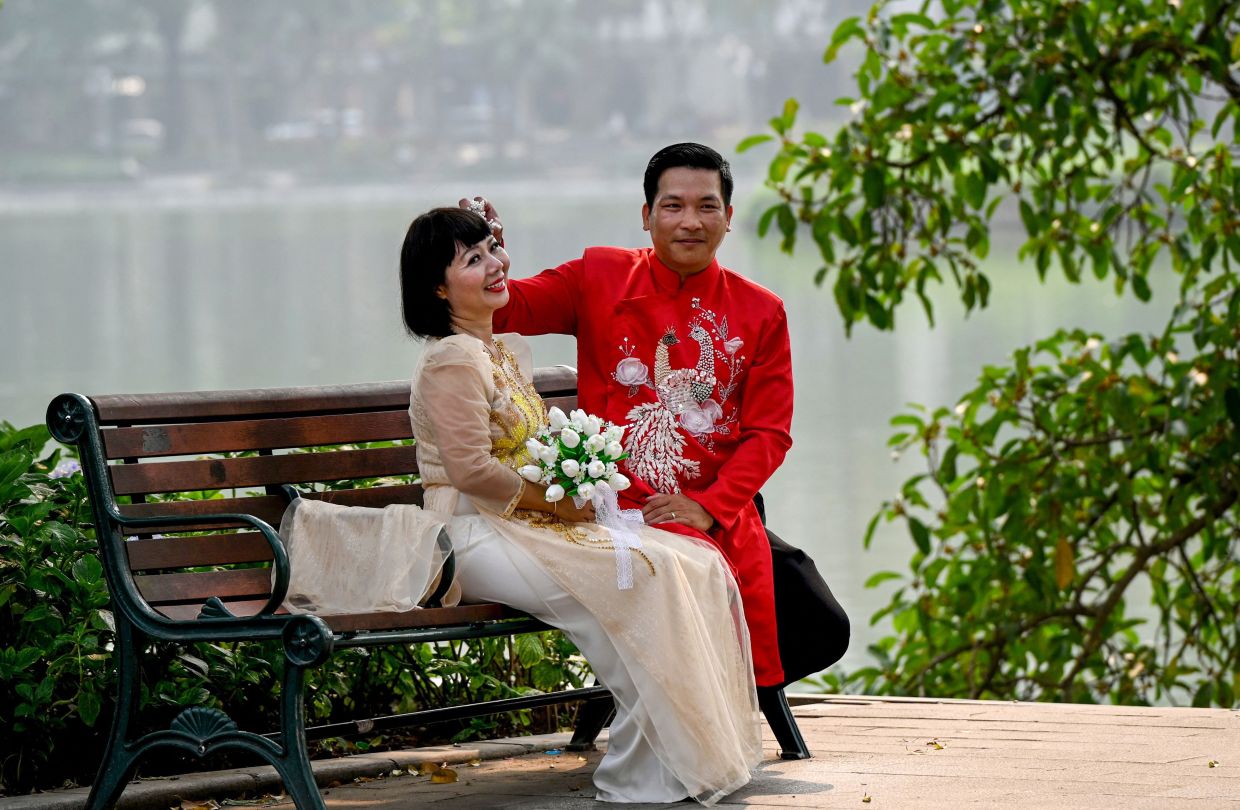 A couple poses for a photo at Hoan Kiem Lake in Hanoi on Monday, April 6, 2026. -- Photo by Nhac NGUYEN / AFP