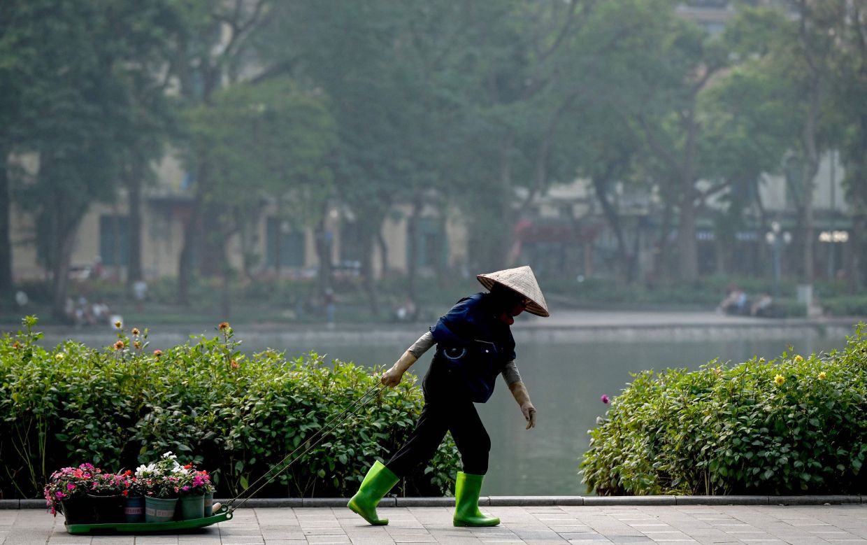 A worker drags flower pots along Hoan Kiem Lake in Hanoi. --Photo by Nhac NGUYEN / AFP