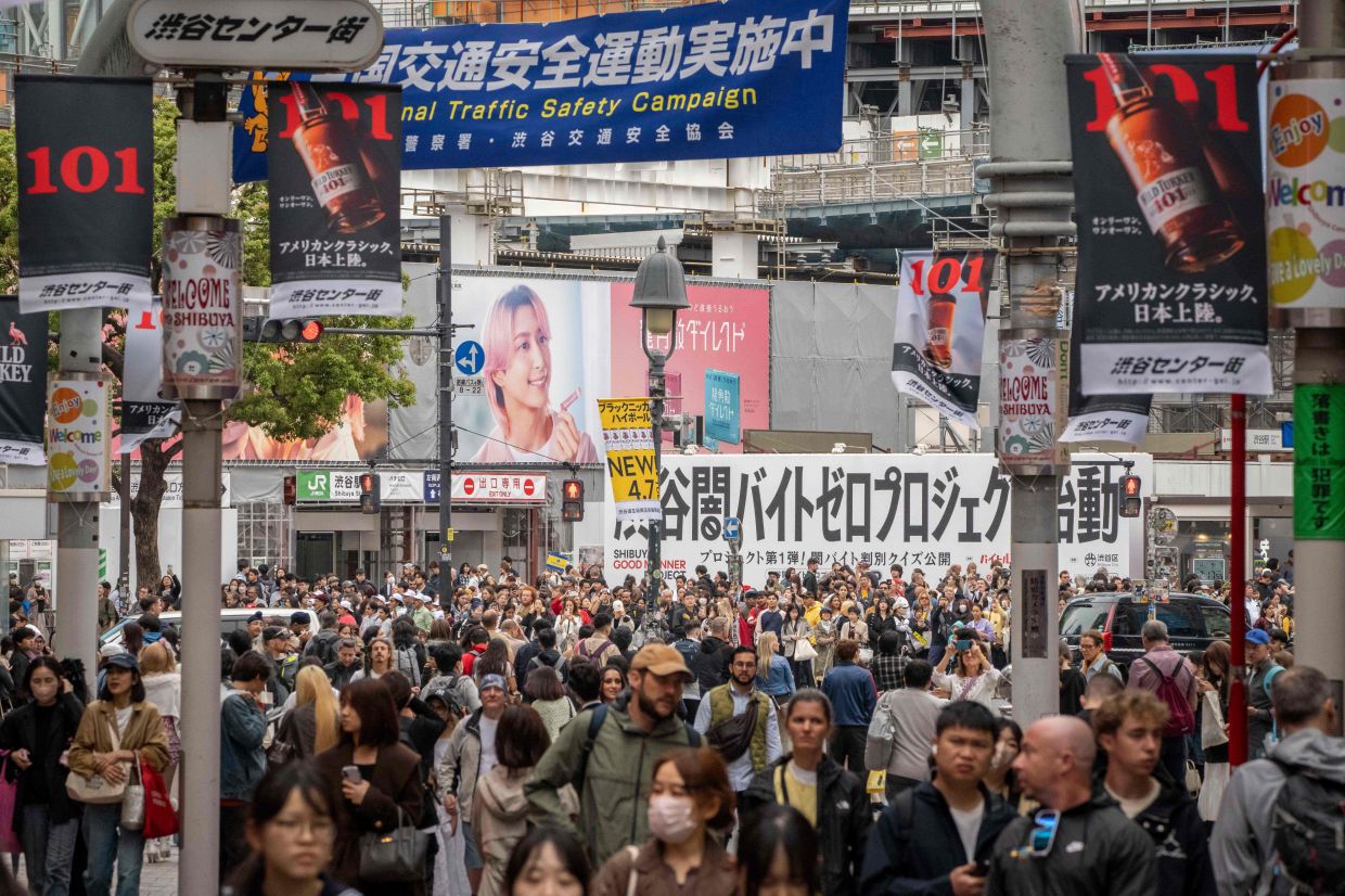 People walk through Shibuya area in Tokyo on April 7, 2026. (Photo by Yuichi YAMAZAKI / AFP)