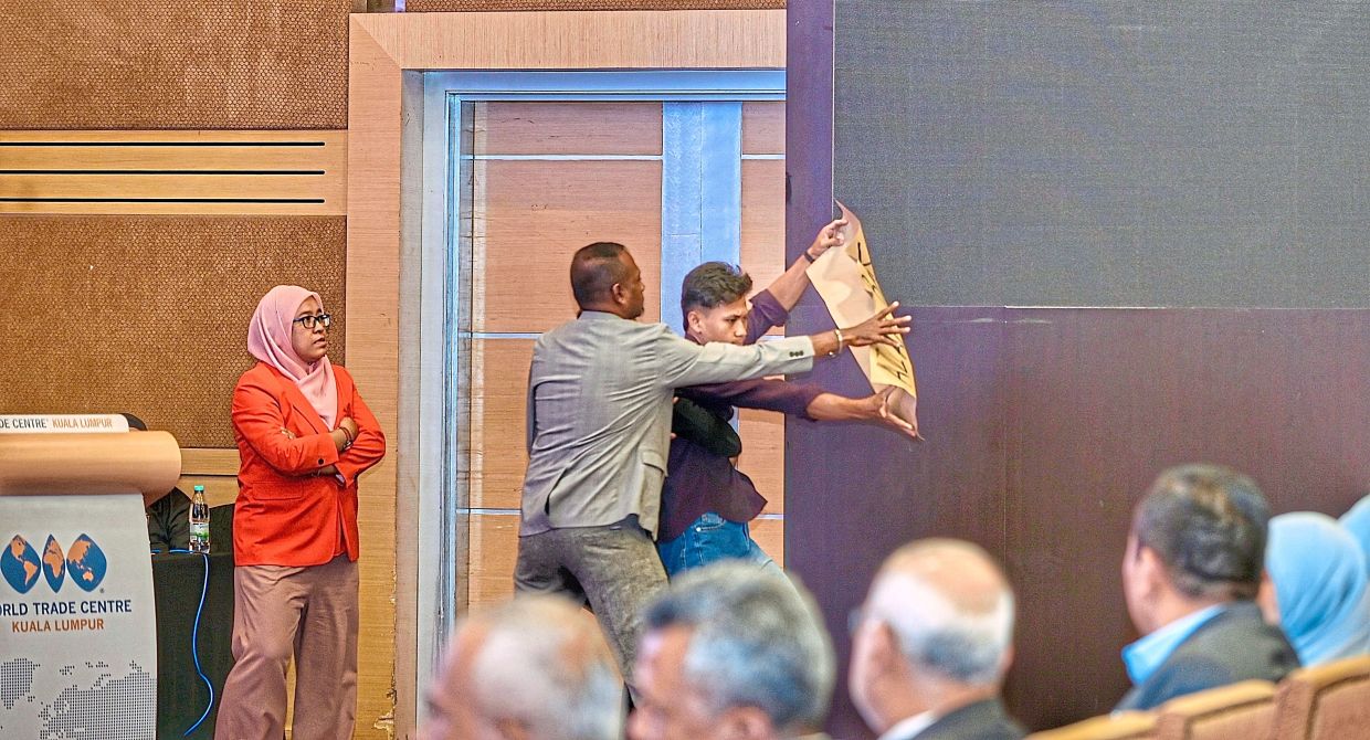 The show must go on: A protester being removed by security during Azam’skeynote address at the programme held at the World Trade Centre in Kuala Lumpur. — RAJA FAISAL HISHAN/The Star