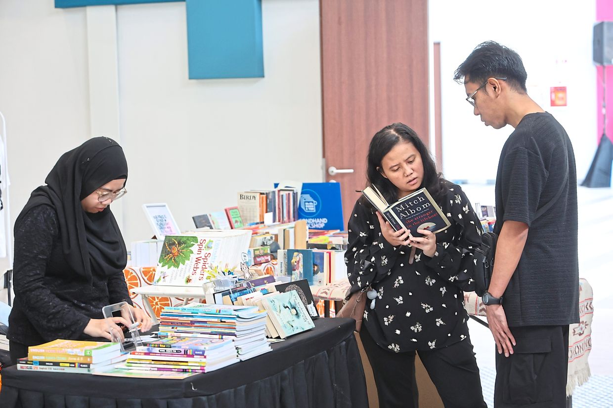 Zulaiha (middle) and friend Amirul Azri checking out a book at the market.