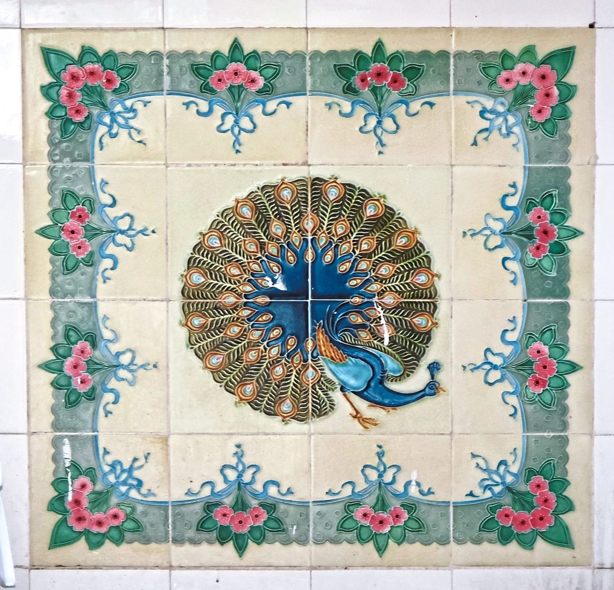 A set of antique ceramic tiles in the washroom, embellished with a circular, hand-painted peacock and floral motifs.