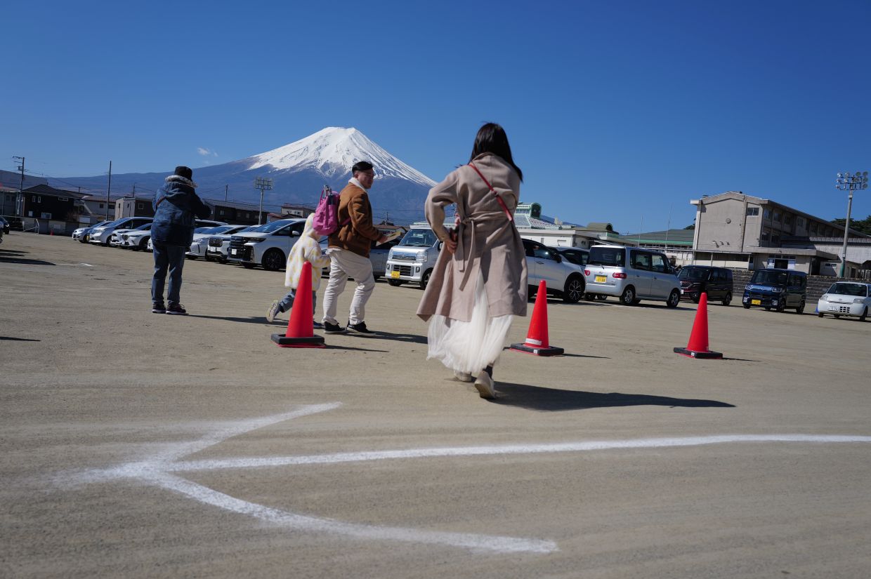 Foreign visitors looking at Mount Fuji from a car park near Shimoyoshida Station in Fujiyoshida, Yamanashi Prefecture. Photos: AP 