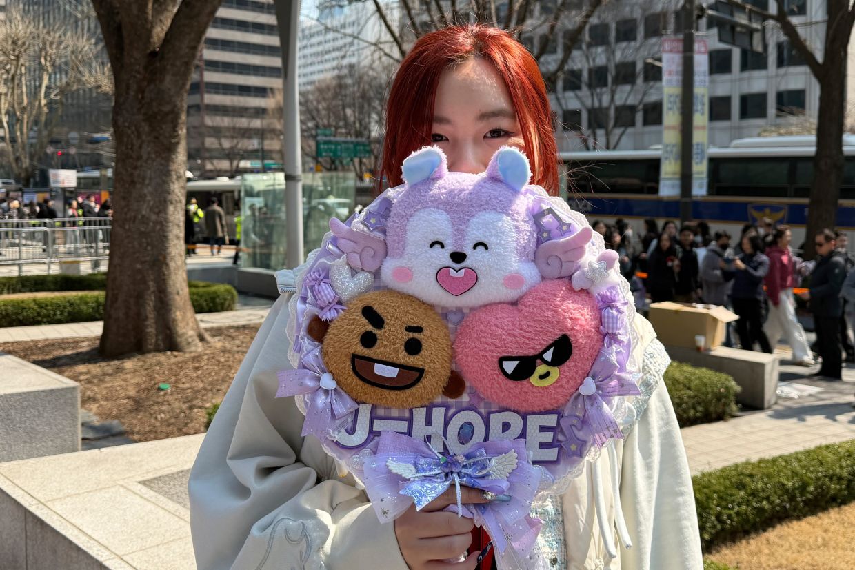 Han Yunyi, a BTS fan originally from Jiangsu province in China, poses for a photo holding BTS fan merchandise after BTS's comeback concert near Gwanghwamun Square in Seoul, South Korea. -- AP Photo/ Juwon Park