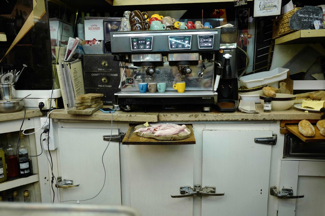 A coffee machine and slices of ham on a wooden board at Le Petit Vendome cafe bistrot during lunch time in Paris on September 16, 2025.— Photo by Ludovic MARIN/ AFP