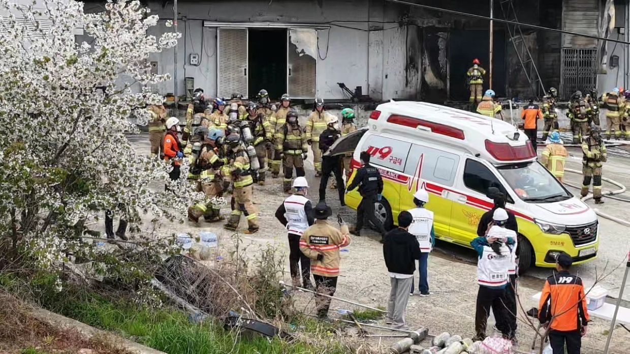 Firefighters watch as their colleague is carried to an ambulance. Two firefighters died in the blaze. - Photo: Yonhap