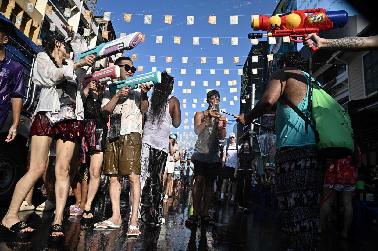 Revellers take part in mass water fights on the eve of the Songkran, or Thai New Year, on Khao San Road in Bangkok on Sunday, April 12, 2026. -- Photo by Lillian SUWANRUMPHA/ AFP