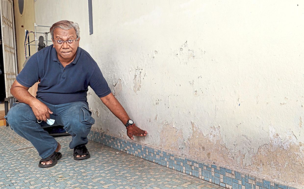 Patrick pointing to the water mark along the wall of his driveway.