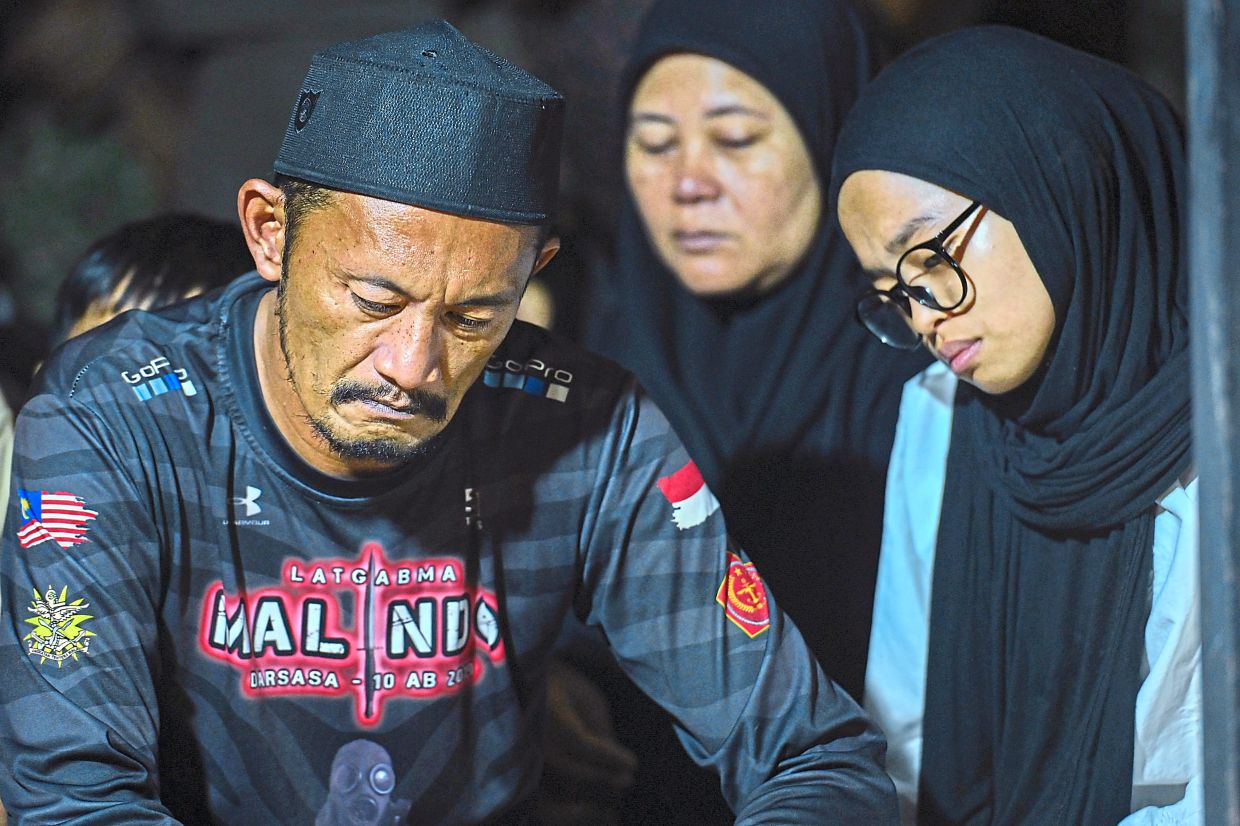 The deceased’s father, Rosafindi Tambi Chik, and other family members during the funeral at the Felda Sungai Kelamah Cemetery in Gemas. — Bernama