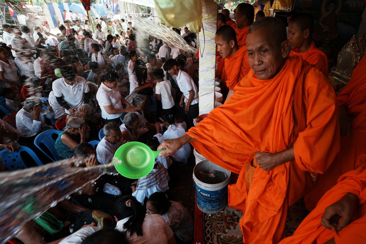 Residents of Prey Popel village receive holy water from Buddhist monks (right), a ritual believed to bring good luck, during the Khmer New Year celebrations on the outskirts of Phnom Penh, Cambodia. -- AP Photo/Heng Sinith