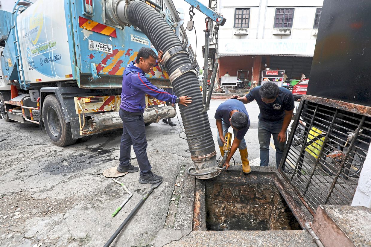 Workers removing sludge from a drain in Bandar Sungai Long, Kajang.