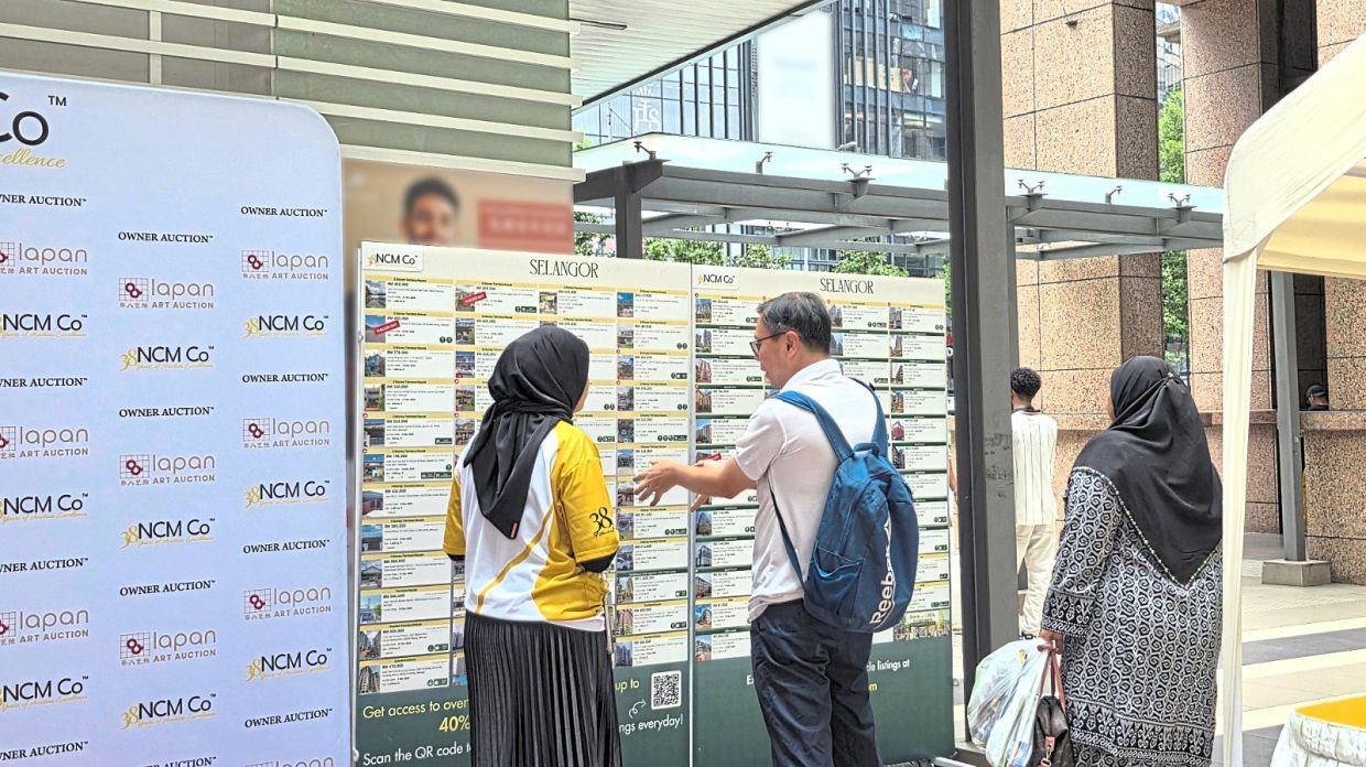 A visitor discusses available Selangor properties with an NCM Co representative at the NCM Co Auction Carnival in Kuala Lumpur.