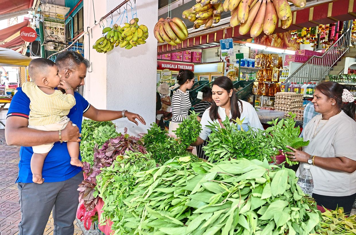 (From left) Yuvaraj Chandra Segaran, his eight-month-old son Rutvaraaj, wife Kayathri Shamugam and mother Devikar Letchumanan buying ingredients for a vegetarian spread.