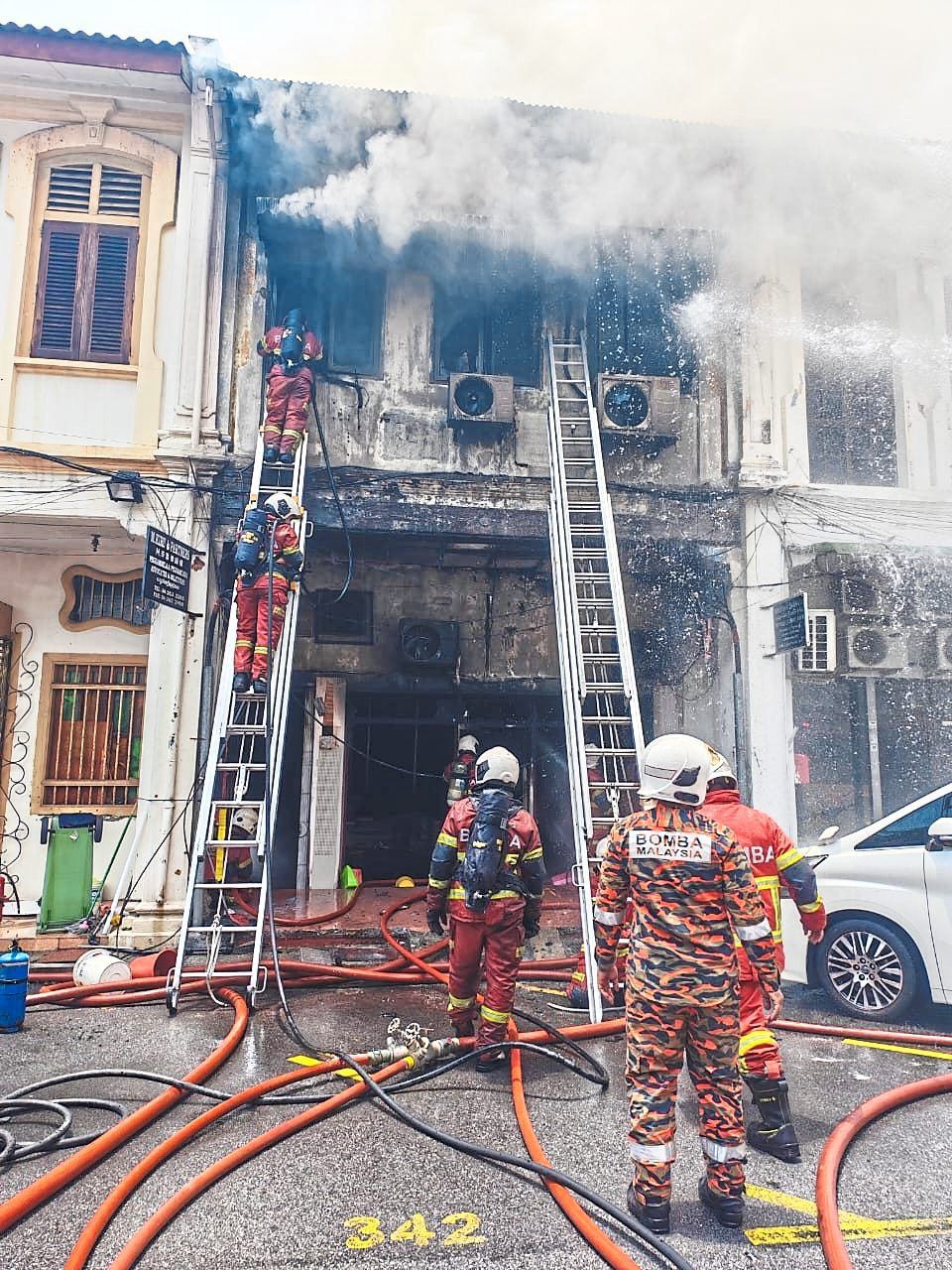 Devastating aftermath: Fire and Rescue department personnel putting out the fire at a pre-war house along Lebuh King.