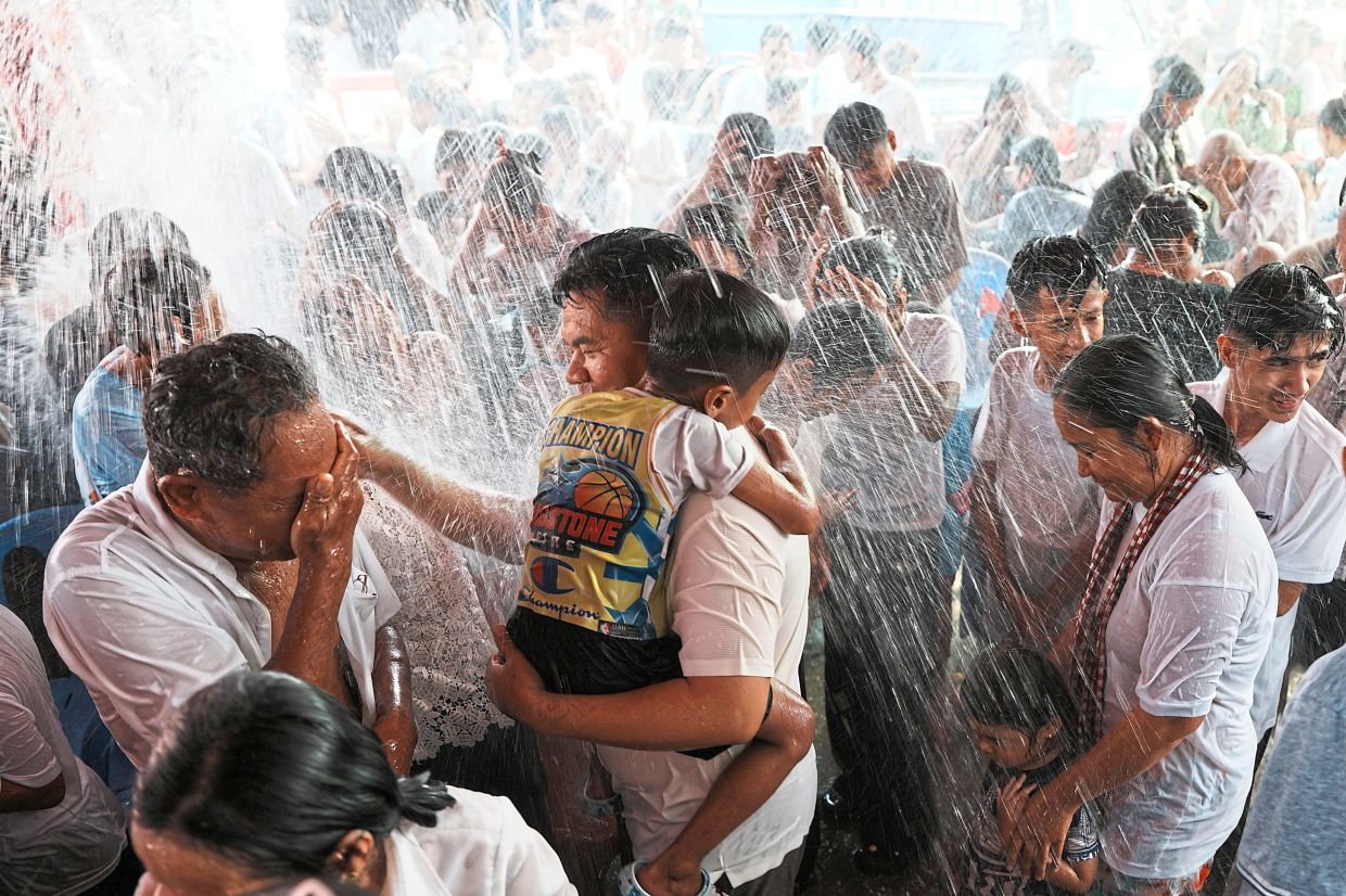 Villagers receiving a holy water shower, believed to bring good luck, near Phnom Penh, Cambodia.— AFP