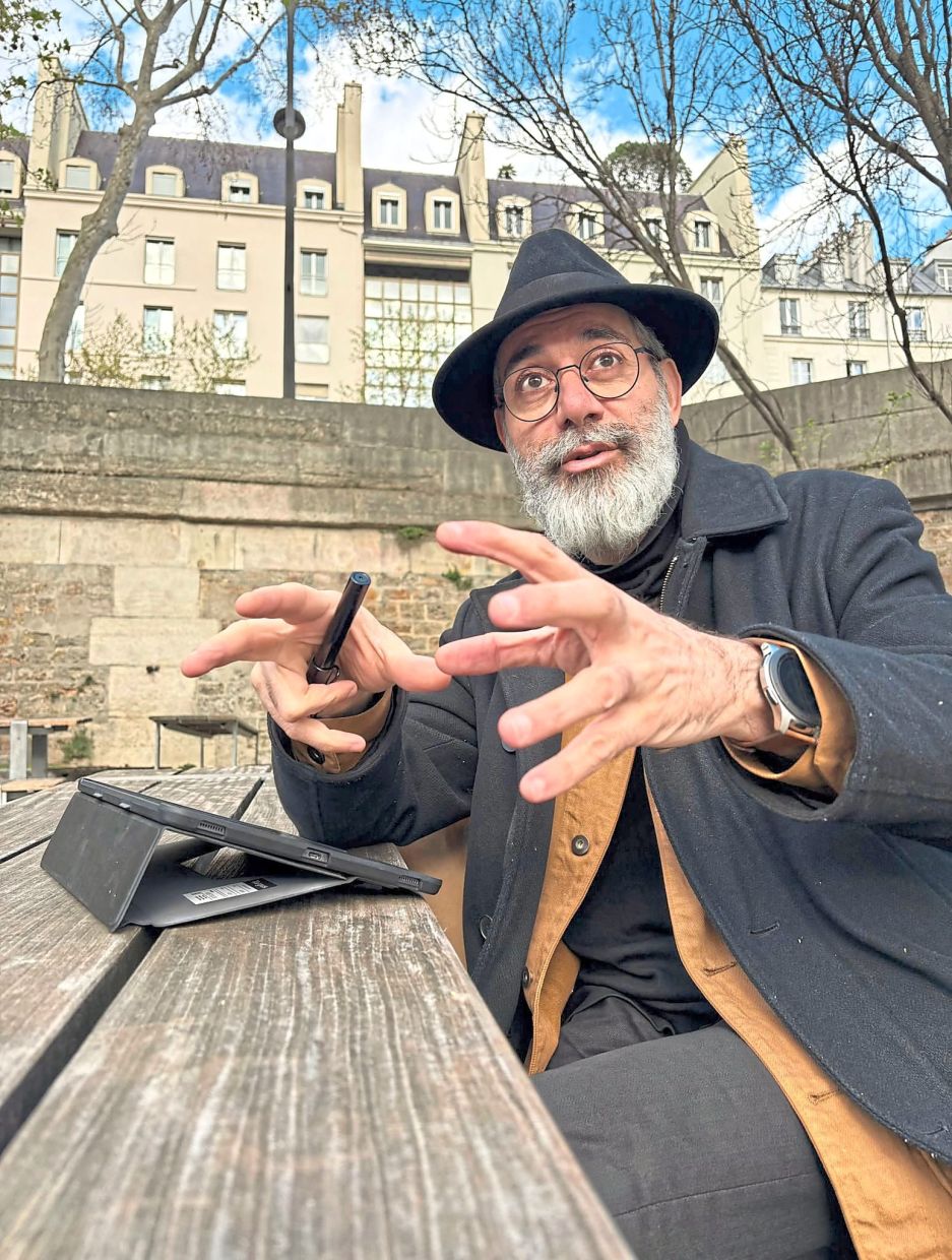 Exiled Iranian political cartoonist Kianoush Ramezani gestures as he sketches on his digital tablet in Paris. Photo: AFP 