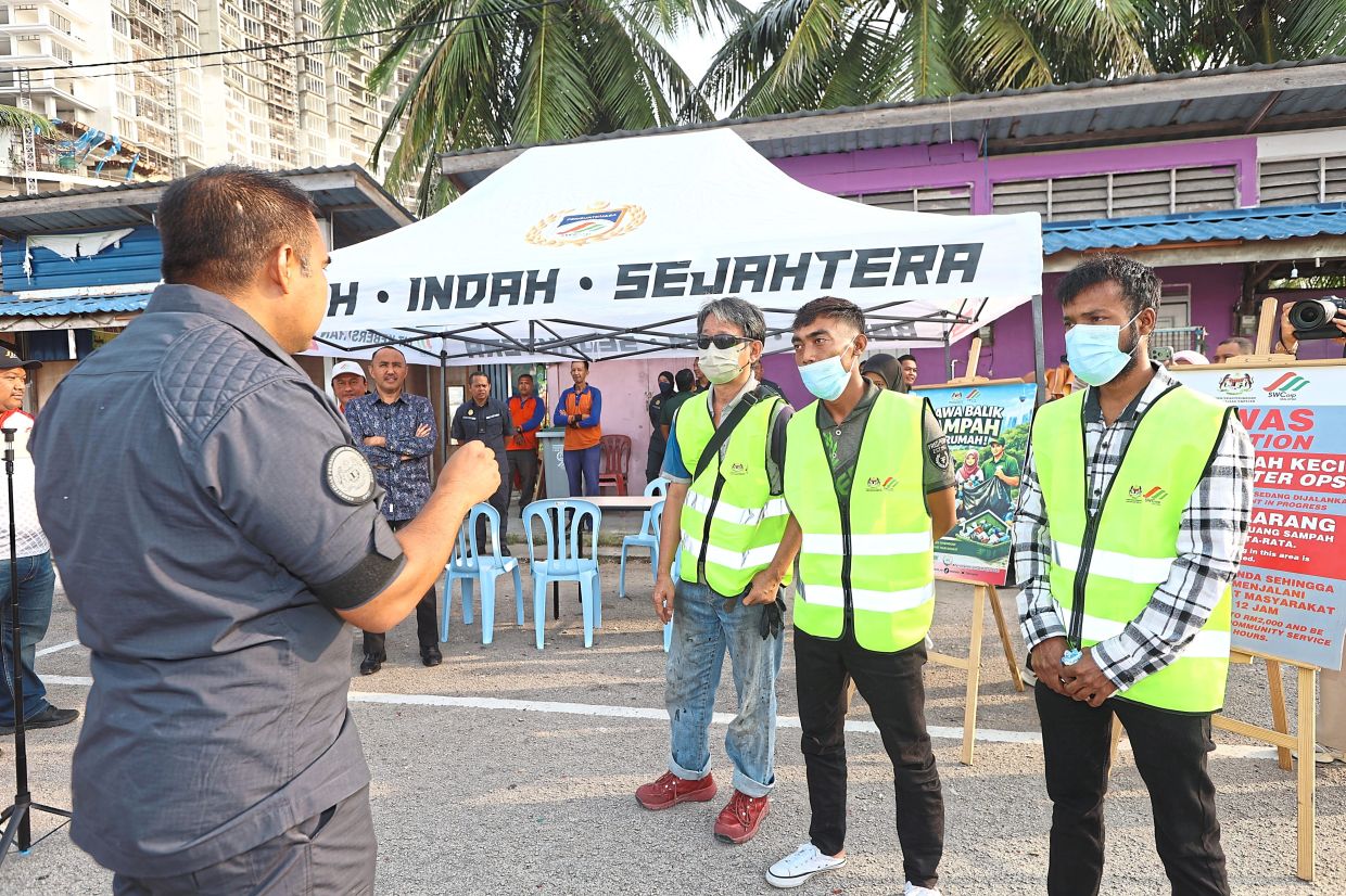 An SWCorp officer briefing three individuals before their community service in Johor Baru.