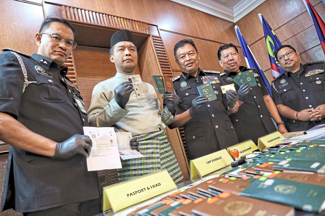 Major discovery: Zakaria (third from left) and Immigration officers showing passports and forged Immigration documents during a press conference in Putrajaya. — MUHAMAD SHAHRIL ROSLI/The Star