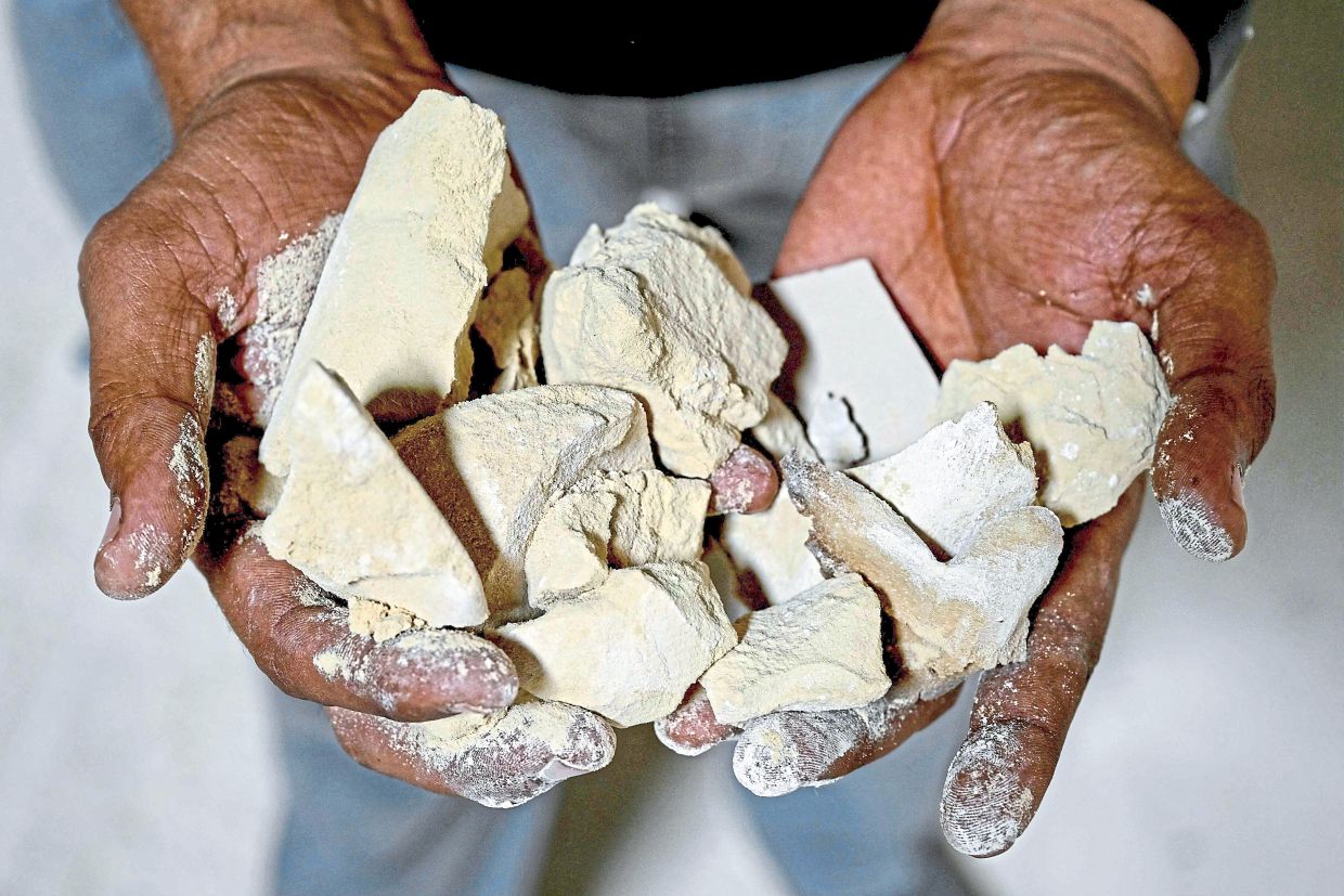 A worker showing clay used to make tiles at a ceramics factory in Morbi. — AFP 