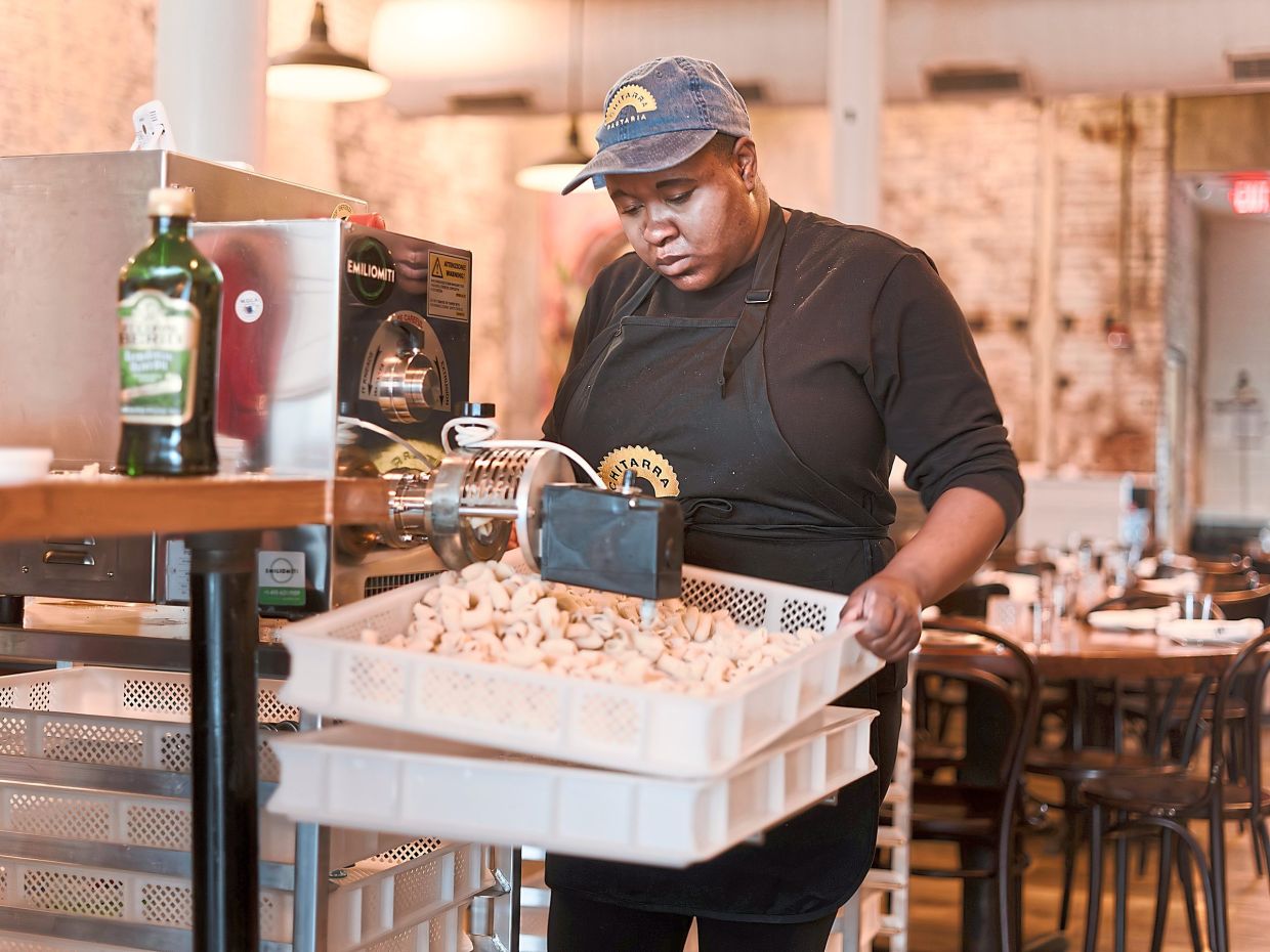 Ezra Kukis works a pasta extruder at Chitarra Pastaria, which tailors jobs to each employee’s skills. 