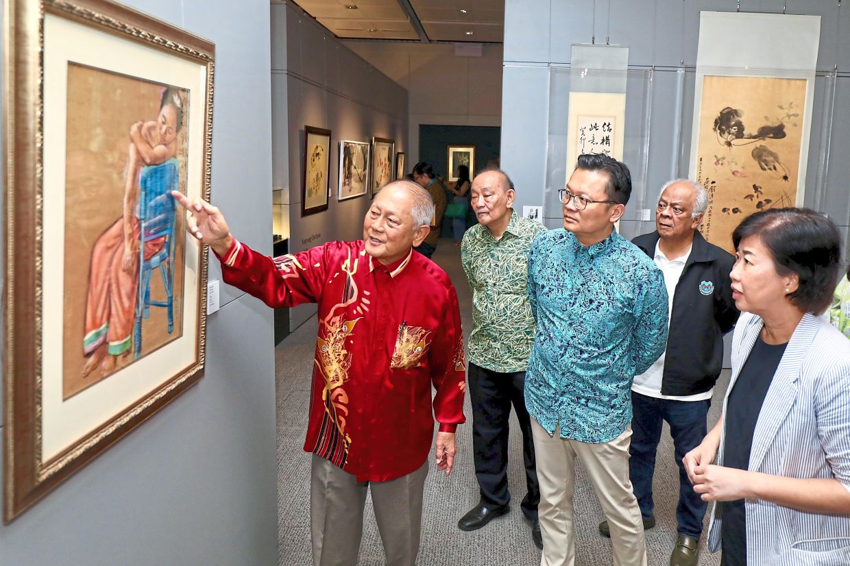 Sim (left) explaining the details of an artwork to Koh (centre) and Yeoh. 