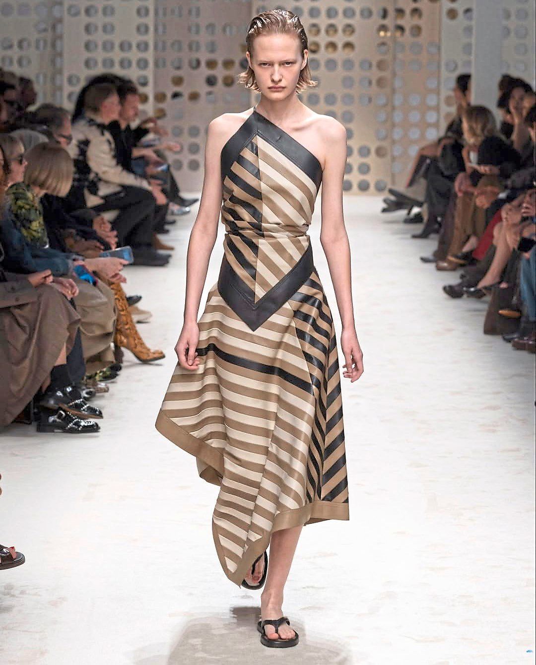 A striped dress in black, brown and beige is crafted to resemble several scarves combined, creating an effect of layered movement and fluidity. Photo: Tod's