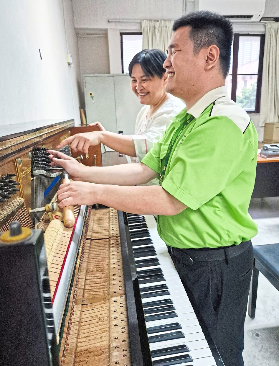 Visually impaired trainee Thew Ming Soon, 27, (right) undergoes piano tuning training with support from Wong. 