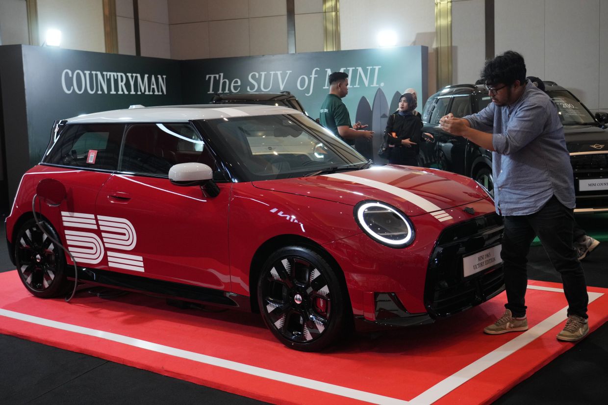A man takes photographs of a MINI 1965 victory edition electric vehicle during its launch event in Jakarta, Indonesia. Friday, April 17, 2026. -- AP Photo/Tatan Syuflana
