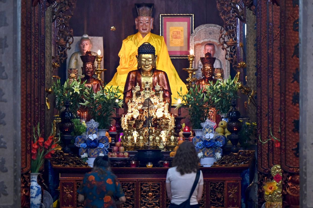 Women pray before a Buddha statue inside a pagoda in Hanoi on Friday, April 17, 2026. -- Photo by Nhac NGUYEN / AFP