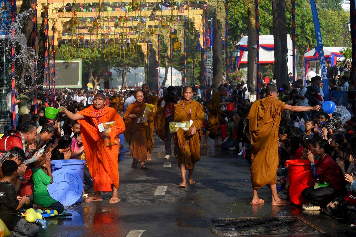 Cambodian Buddhist monks throw water on people during celebrations for the Khmer New Year, known as Nokor Sankranta, in Phnom Penh. -- Photo by TANG CHHIN Sothy / AFP