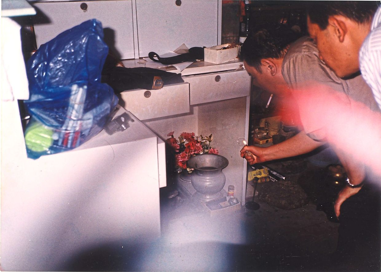 Police examining items inside the house where Mazlan’s body was discovered. — The Star