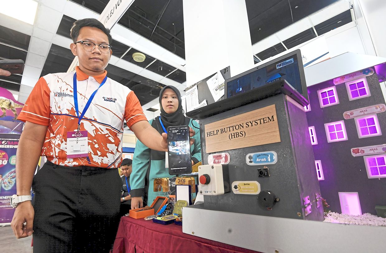Just a touch of a button: Muhammad Razan and Hanna Natalya Maisara showing how their Help Button System project works during the expo. — AZHAR MAHFOF/The Star
