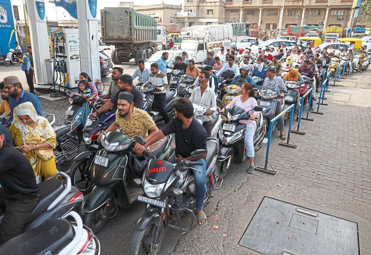 People queueing to fill petrol in their two-wheelers with concerns over potential supply disruptions in Ahmedabad. — Reuters