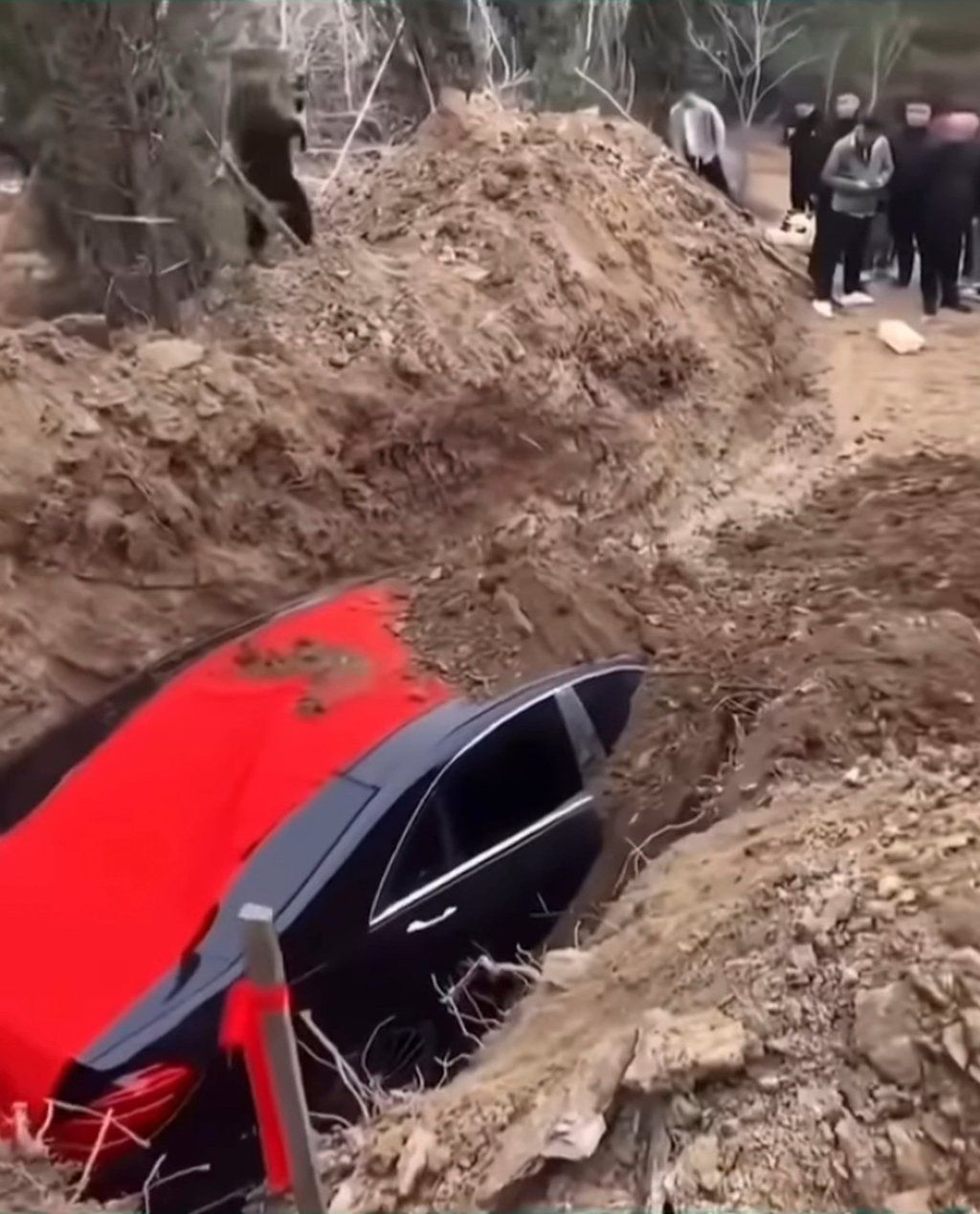 Mourners piled mounds of earth on top of the car, above, as part of the funeral ceremony. - Photo: bilibili.com