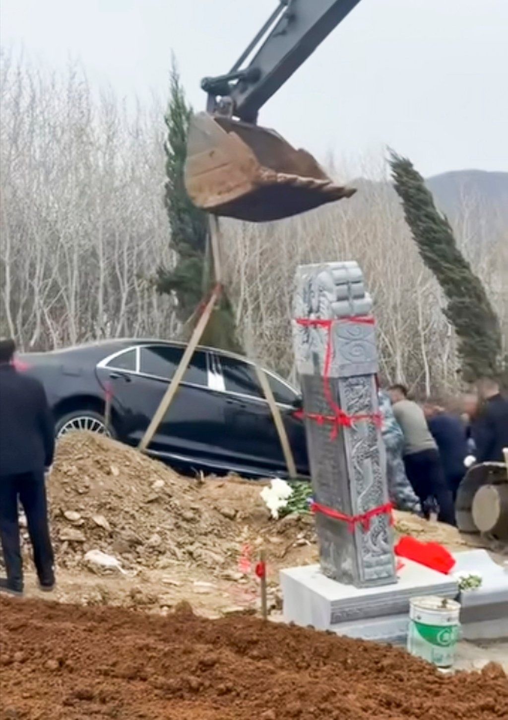 The arm of a mechanical digger lifts the car before it was placed in the “grave”. - Photo: bilibili.com
