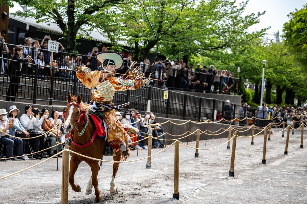 An archer in traditional outfits riding on a horse shoots arrows at a target during the Yabusame horseback archery demonstration of the samurai martial arts at Sumida Park in Tokyo's Asakusa area on Sunday, April 18, 2026. -- Photo by Philip FONG / AFP