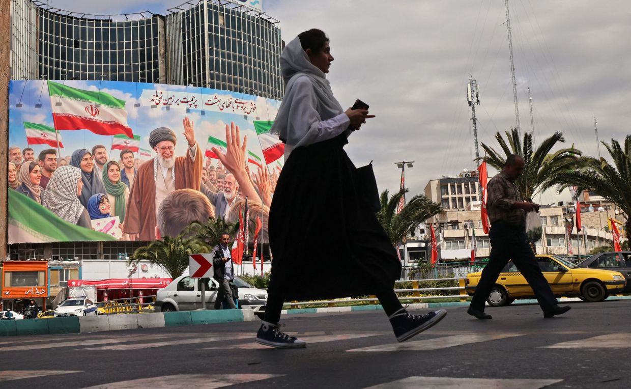 Commuters make their way past a giant billboard of slain Iranian supreme leader Ayatollah Ali Khamenei at the Valiasr Square in Tehran on April 19, 2026. The strategic Strait of Hormuz was again closed on April 19 in the stand-off between Iran and the United States, with Iran's powerful parliament speaker signalling a final peace deal remained far off despite some movement in negotiations. -- Photo by ATTA KENARE / AFP