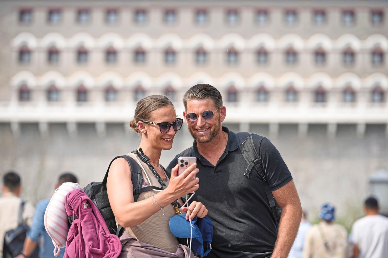 Foreign tourists pose for a selfie as they stroll along the Qianmen pedestrian shopping street, in Beijing. 