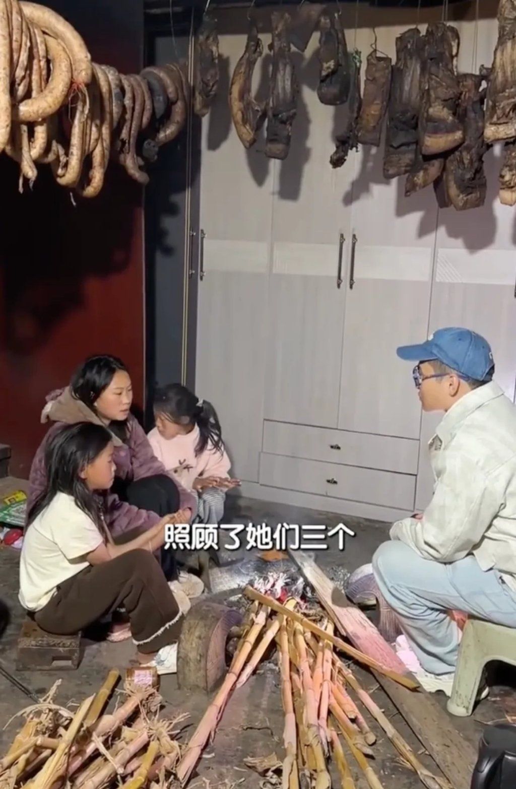 Chen Jiajun, right, chats with Aji and her sisters as they sit around a rudimentary fire. - Photo: Weibo