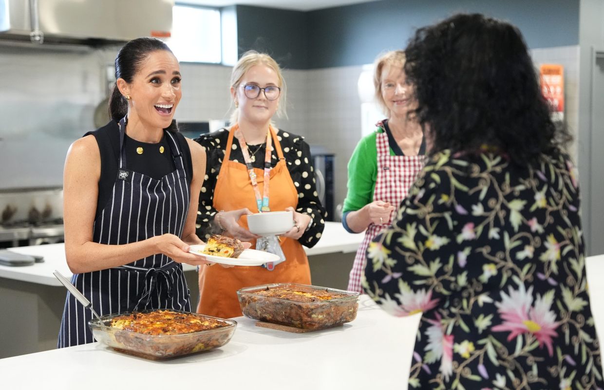 Meghan Markle, left, the Duchess of Sussex, alongside staff members, serves lunch to a resident during a visit to McAuley Community Services for Women, a women's homeless and family violence shelter in Footscray, a suburb of Melbourne, Australia Tuesday, April 14, 2026. Photo: AP