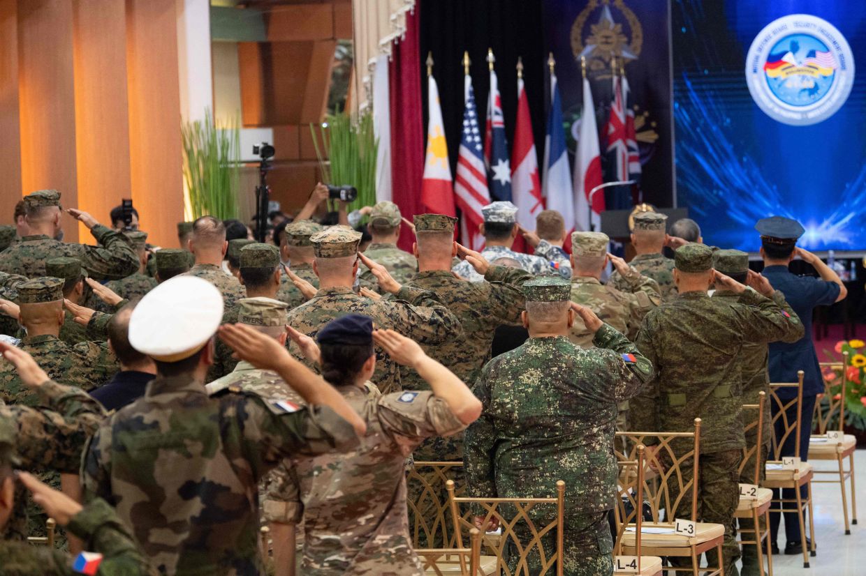 Philippine and US soldiers salute as their national anthems are played during the opening ceremony of the annual Balikatan (shoulder to shoulder) joint military exercise at Camp Aguinaldo in Quezon city, suburban Manila on Monday, April 20, 2026. Thousands of American and Philippine troops, joined for the first time by a significant contingent of Japanese forces, began annual military exercises on April 20 set against the backdrop of the Middle East war. -- Photo by Ted ALJIBE / AFP