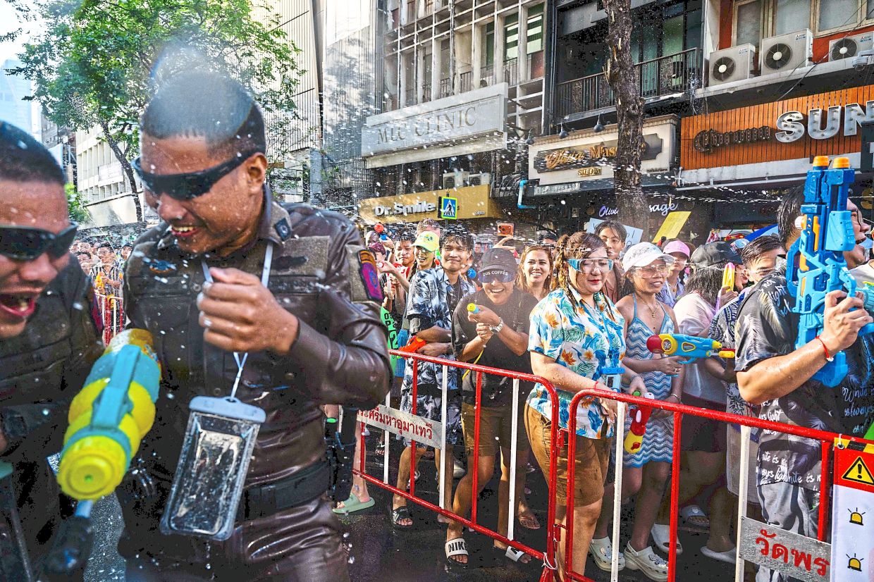 Police officers are a familiar sight in Songkran celebrations, joining in the water-soaked revelry. — AFP