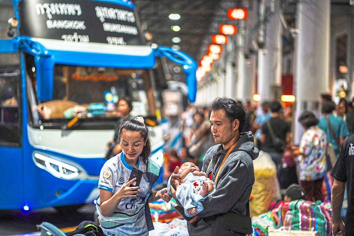 A couple cradles their infant as they wait to board a bus at Mo Chit terminal, joining crowds returning home for the Thai New Year holiday. — Reuters