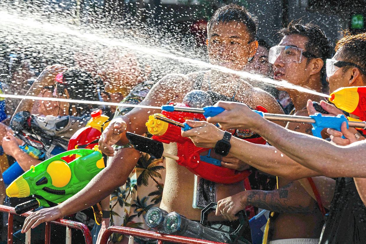 Revellers dousing each other in a chaotic, joyful mass water fight marking Songkran celebrations. — AFP
